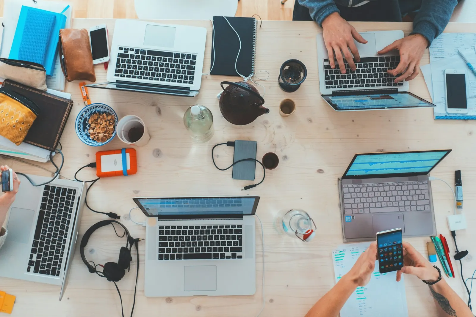 A desk seen from above with laptops and paperwork